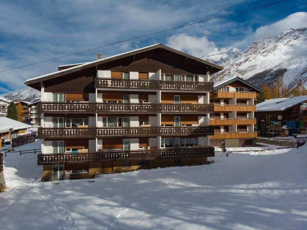 a building in the snow in front of a mountain at Haus Alfa in Saas-Fee