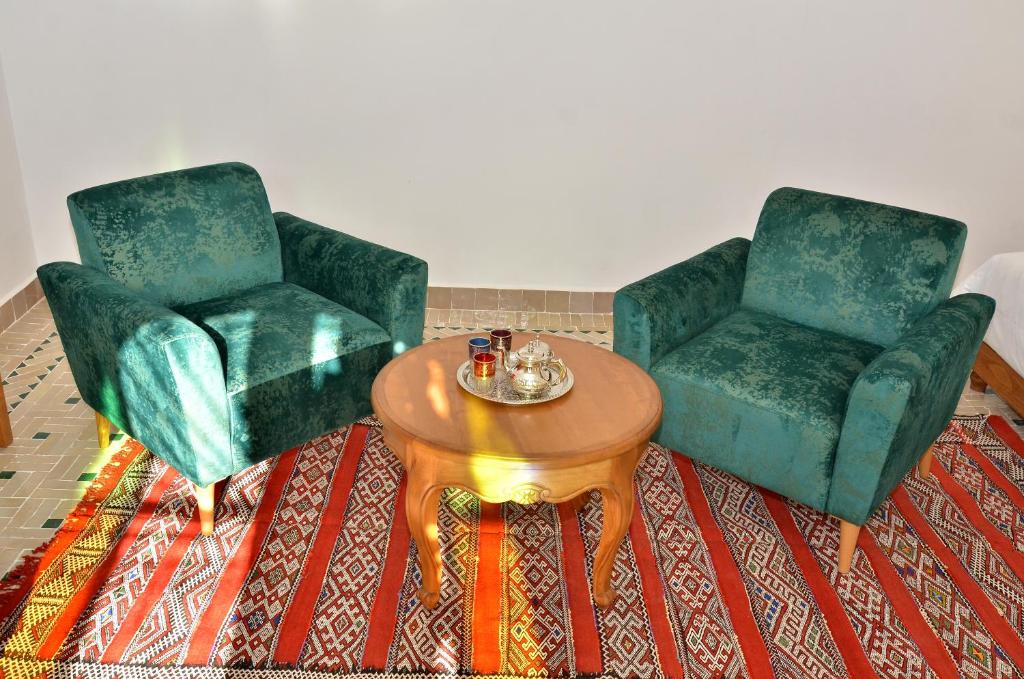 two green chairs and a table in a room at Riad Al Ansari in Fez