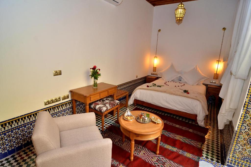 a bedroom with a bed and a couch and a table at Riad Al Ansari in Fez