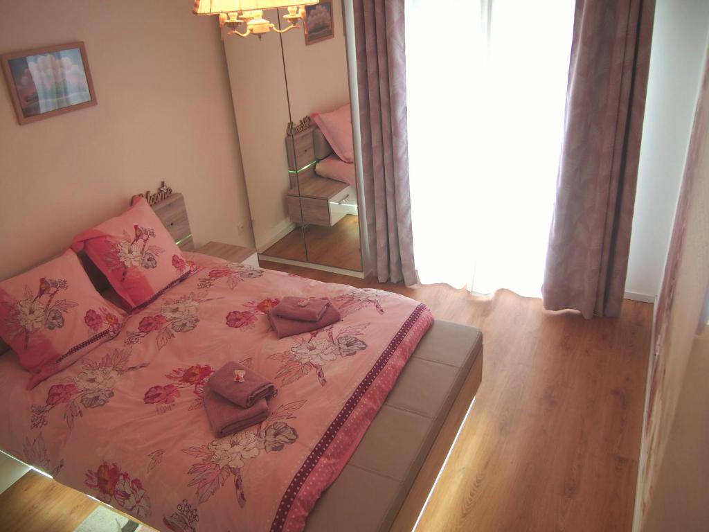 a bedroom with a bed with pink sheets and a mirror at Le Carré des oiseaux in Strasbourg