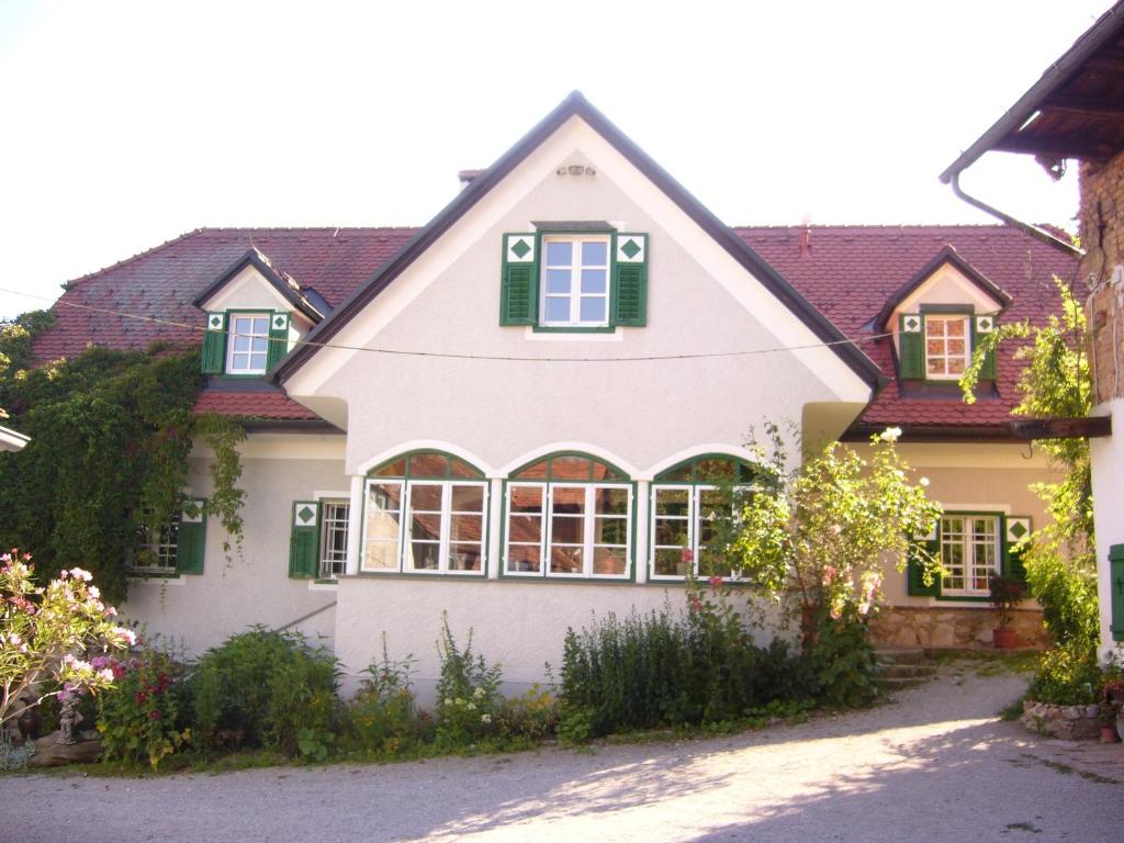 ein großes weißes Haus mit grünen Rollläden darauf in der Unterkunft Hirschenhof in Graz