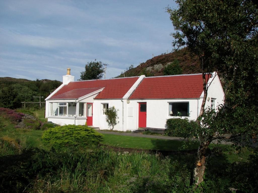 una casa blanca con techo rojo en un campo en Tigh-na-Mara, en Lochinver