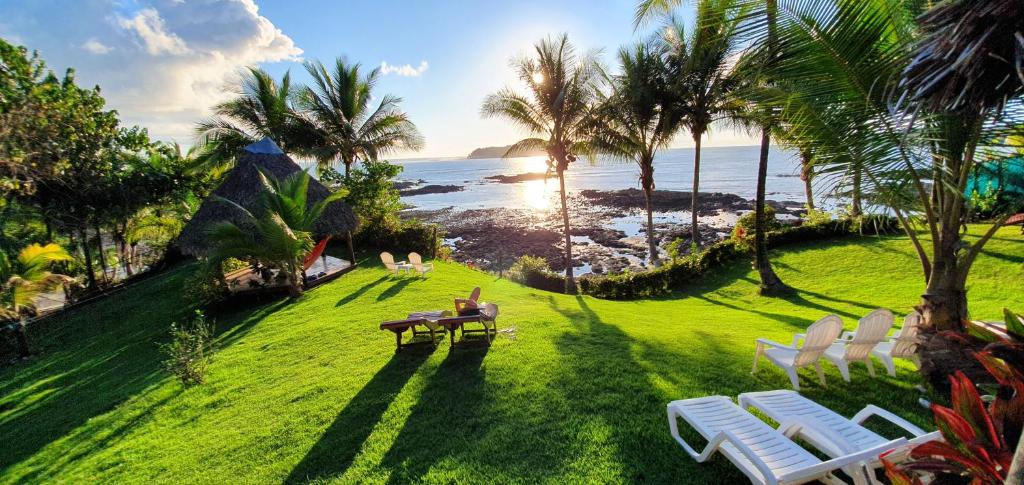 a person sitting on a bench on a lawn near the ocean at Vista Coiba Villas & Restaurant in Santa Catalina