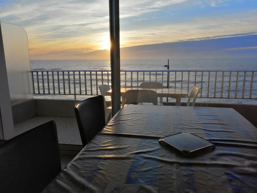 - une table avec un livre sur le balcon donnant sur l'océan dans l'établissement Appartement pour 4, plage des 5 Pineaux, à Saint-Hilaire-de-Riez