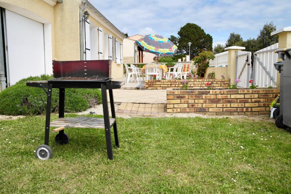 濱海布朗的住宿－Maison idéale pour des vacances en famille revigorantes à Brem-sur-Mer，草地上带椅子的烧烤架
