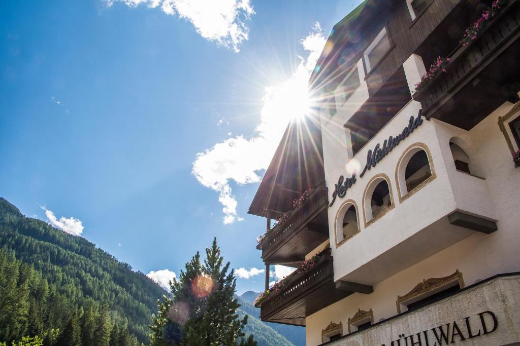 un bâtiment avec le soleil dans le ciel dans l'établissement Hotel Mühlwald, à Selva dei Molini