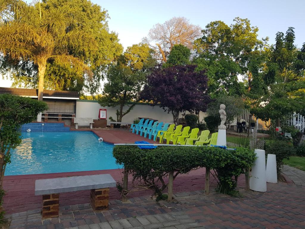 a swimming pool with colorful chairs and a bench at Good 2 Go Guest House in Benoni