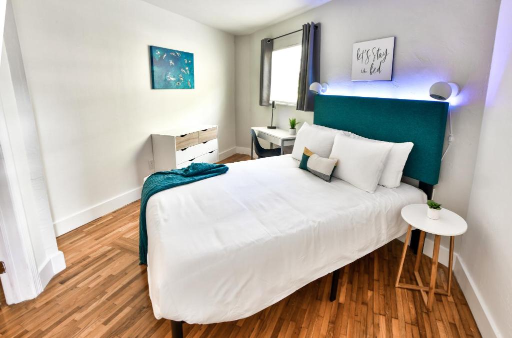 Schlafzimmer mit einem großen weißen Bett mit blauem Kopfteil in der Unterkunft Broadwaysuites Downtown By RocketStay in Miami