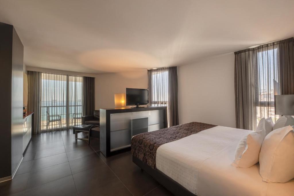 a hotel room with a bed and a desk with a television at RR Hotel da Rocha in Portimão