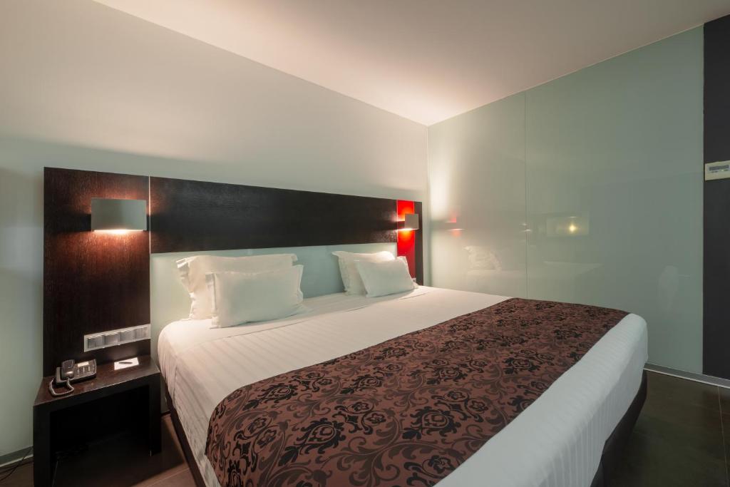 a hotel room with a large bed with white sheets at RR Hotel da Rocha in Portimão