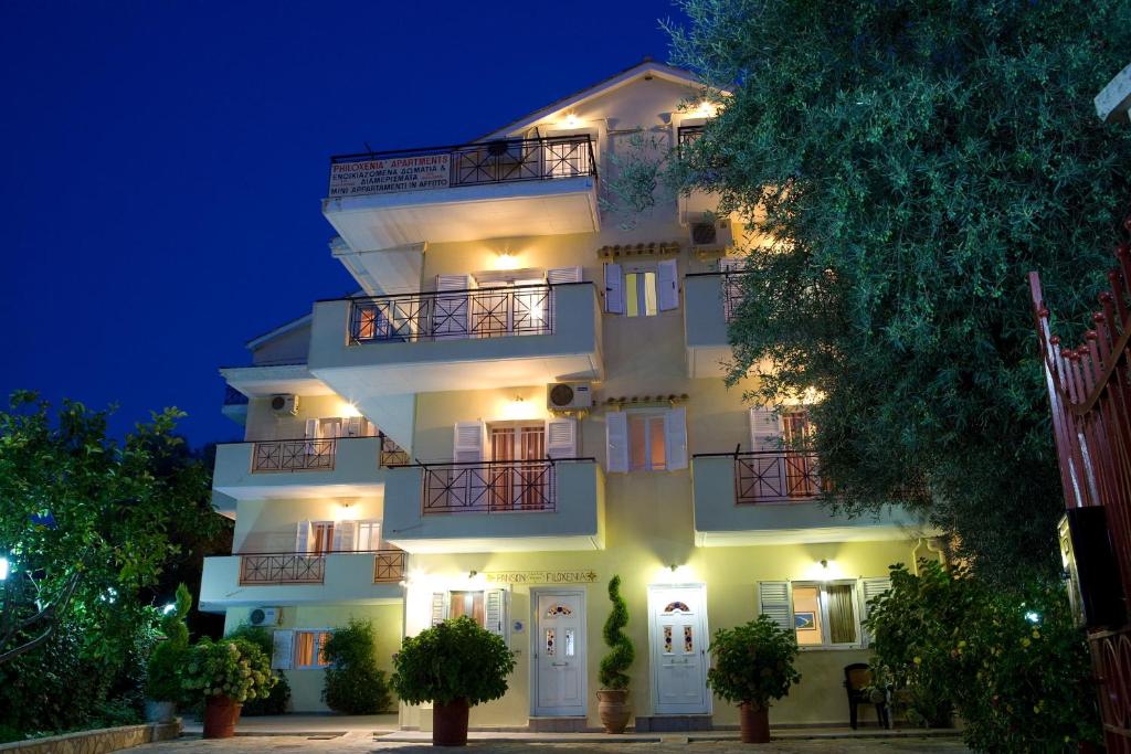 un grande edificio bianco con luci accese di notte di Pansion Filoxenia Apartments & Studios a Tsoukalades