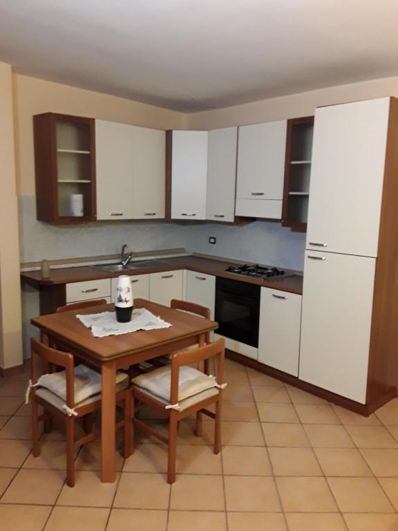 cocina con armarios blancos y mesa de madera en Casa vacanze Martina & Diana, en Aosta