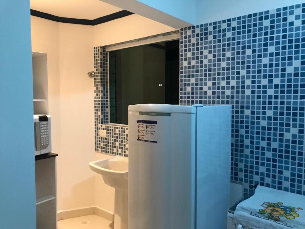 uma casa de banho em azulejos azuis com um frigorífico e um lavatório em Apartamentos Primavera Guarujá no Guarujá