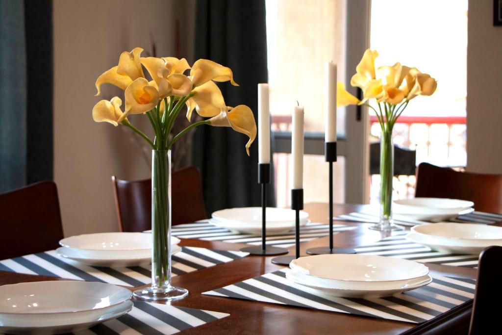 Elegant home in Madinaty compound في القاهرة: طاولة مع الأطباق البيضاء والزهور الصفراء في المزهريات