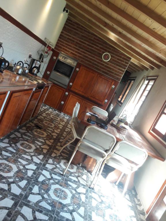 a kitchen with wooden cabinets and white chairs in it at Alojamiento Moni in Mar del Plata