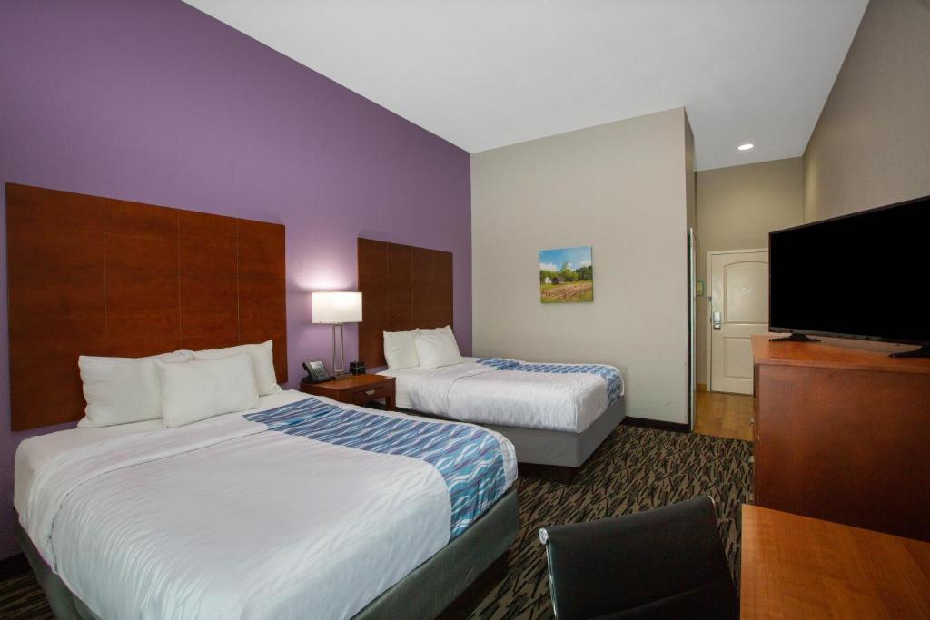 a hotel room with two beds and a flat screen tv at La Quinta by Wyndham Tupelo in Tupelo