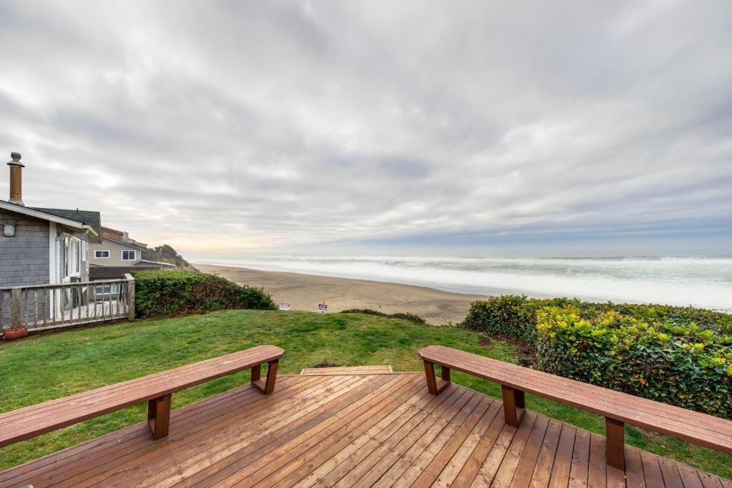 eine Holzterrasse mit einer Bank und Strandblick in der Unterkunft The Best Little Beach House on the Oregon Coast! in Lincoln Beach