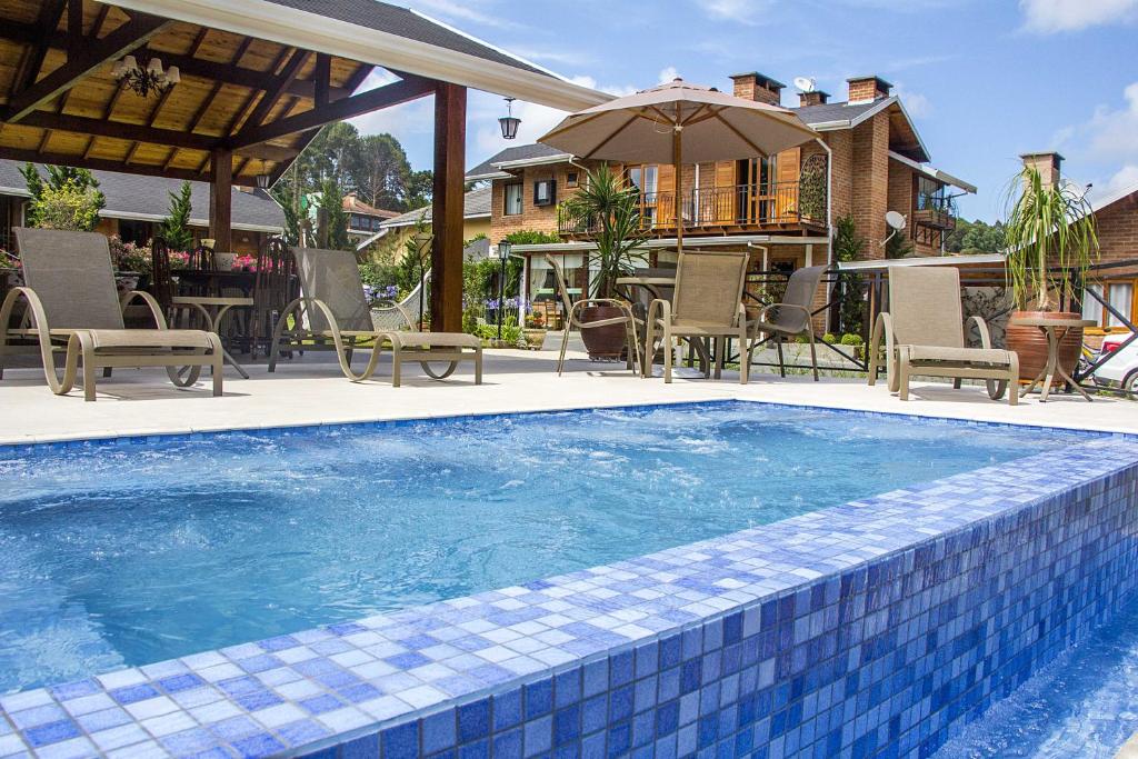 a swimming pool with chairs and a house at Pousada Charme da Serra in Monte Verde