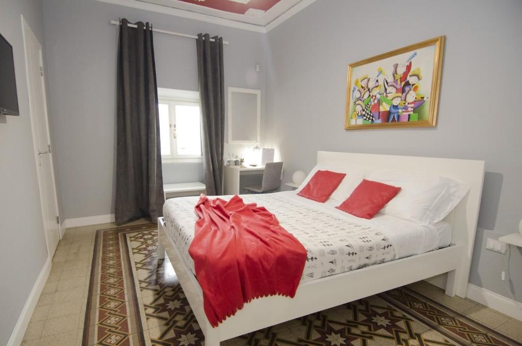 ローマにあるルーム イン バチカンのベッドルーム(白いベッド、赤い枕付)