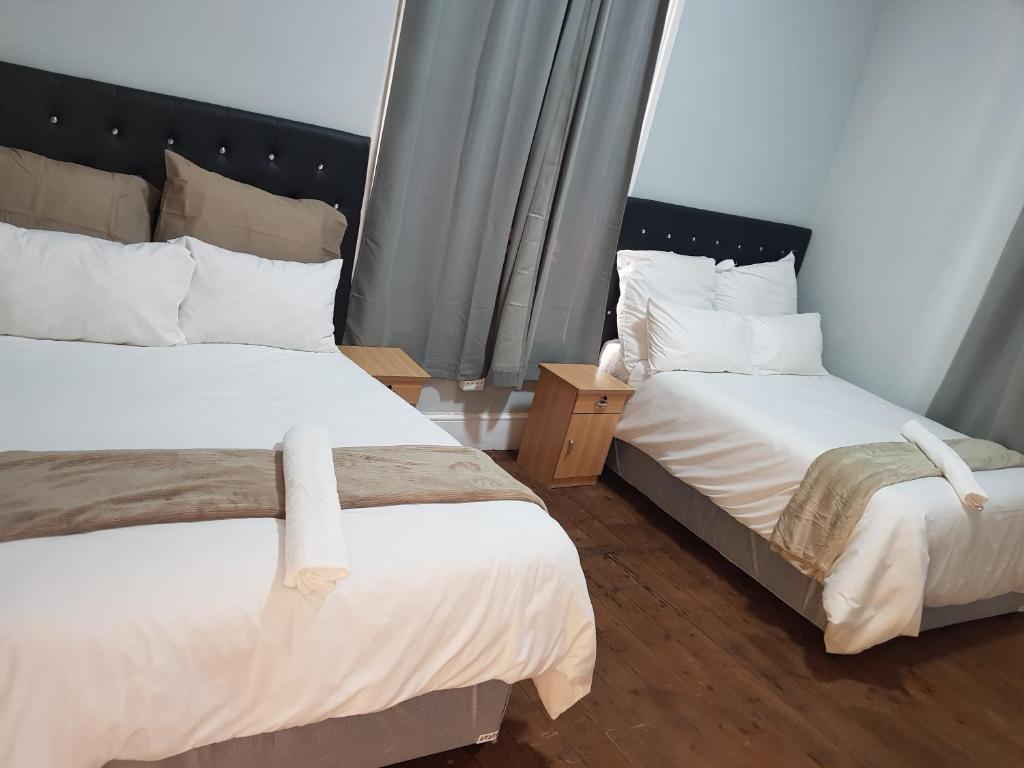 une chambre avec deux lits avec des draps blancs dans l'établissement Helpful lodge, au Cap