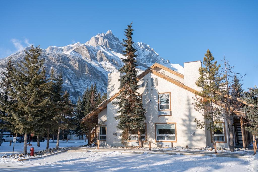 a house in the snow with a mountain in the background at Banff Rocky Mountain Resort in Banff