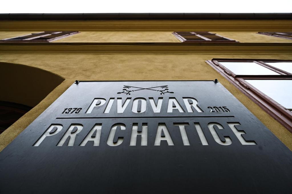 una señal en el costado de un edificio que lee la práctica de la capa en Pivovar Prachatice en Prachatice