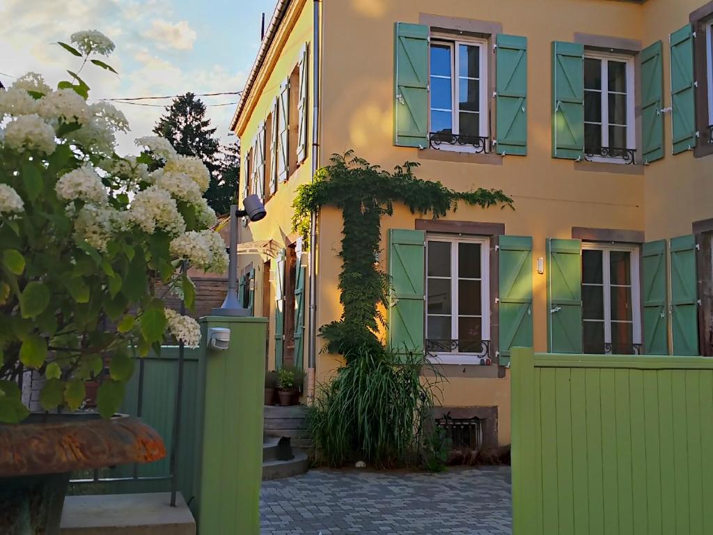 un edificio con finestre verdi e gialle e una recinzione di La Chouette Maison - Chambres d'hôtes et Gîte en Ville a Remiremont