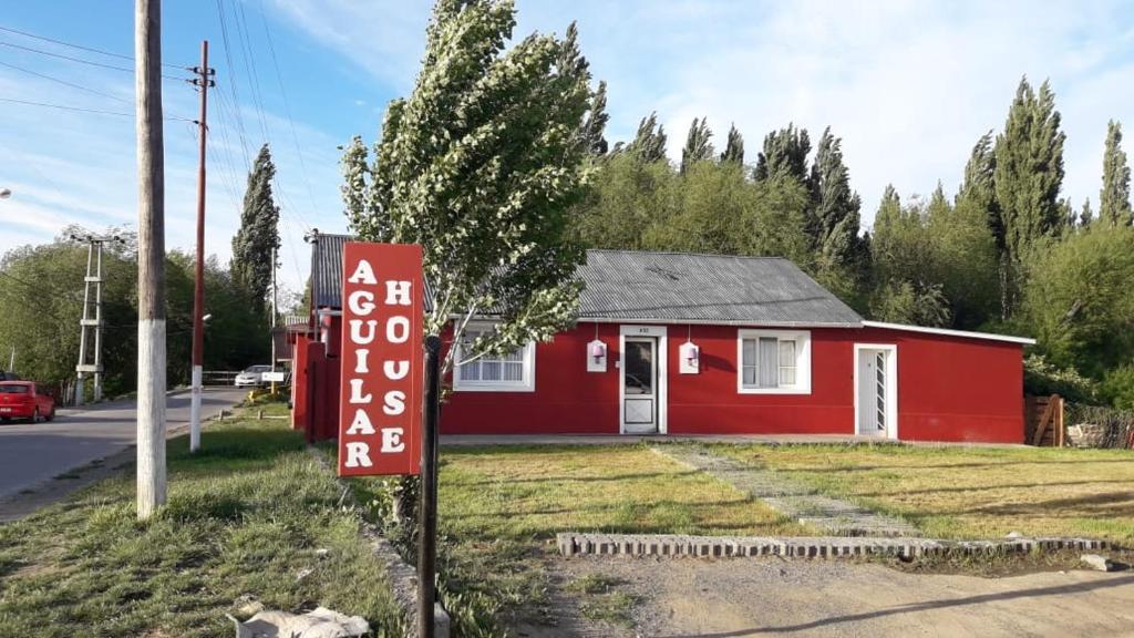 un edificio rojo con un cartel delante en Aguilar House Hostel B&B en El Calafate