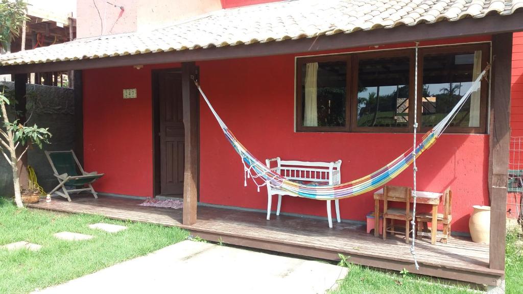 una casa roja con una hamaca en el porche en Casa no Campeche, en Florianópolis