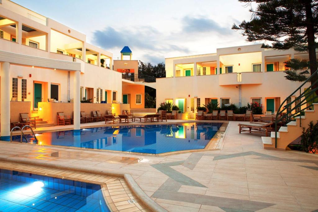 a hotel with a swimming pool in front of a building at Forum Suites in Kato Daratso