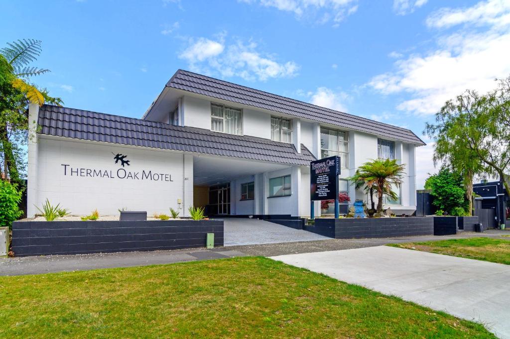 a large white building with a sign on the front of it at Thermal Oak Motel in Rotorua