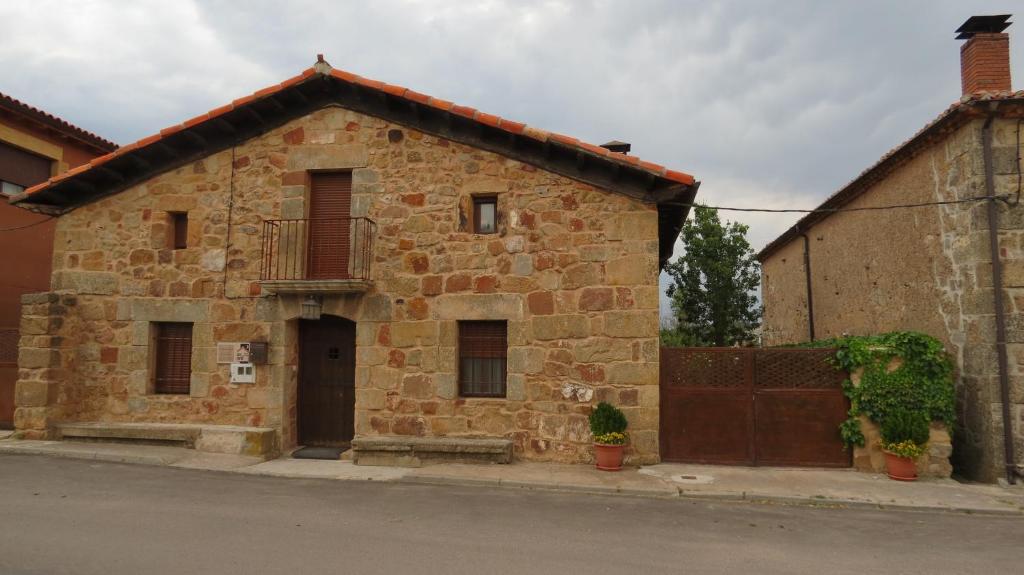un antico edificio in mattoni con balcone su una strada di La Casa de Piedra de la Aldea ad Aldea del Pinar
