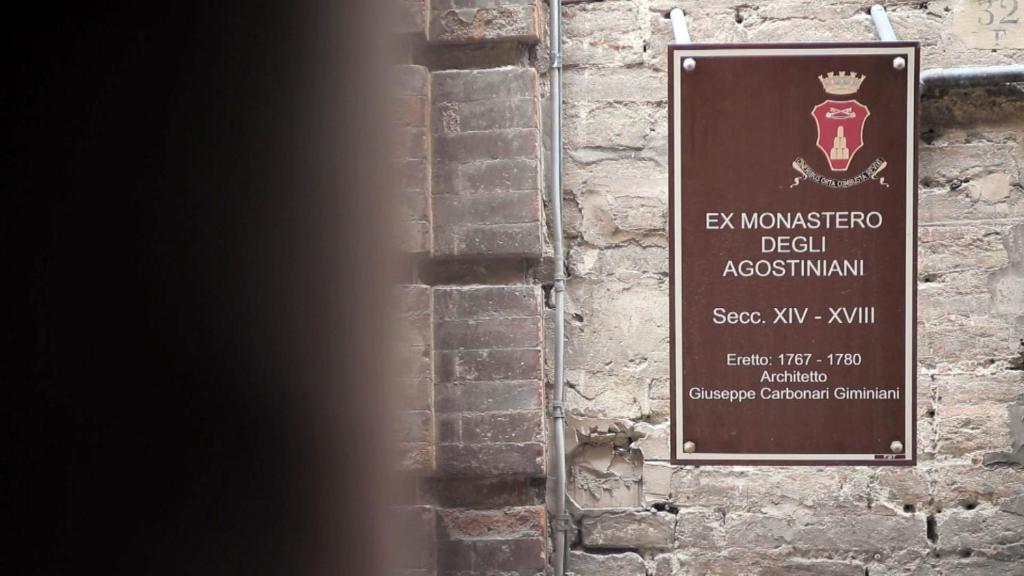a sign on the side of a brick wall at MA Hotel in Corinaldo