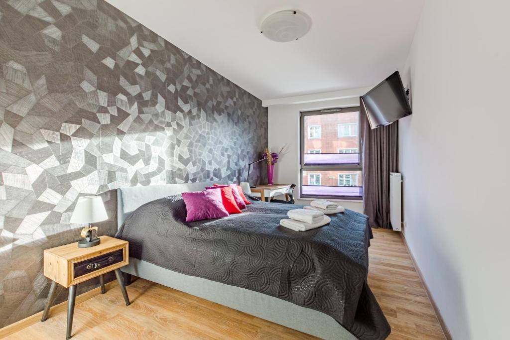 a bedroom with a large bed and a tv at Loft Apartments in Gdańsk