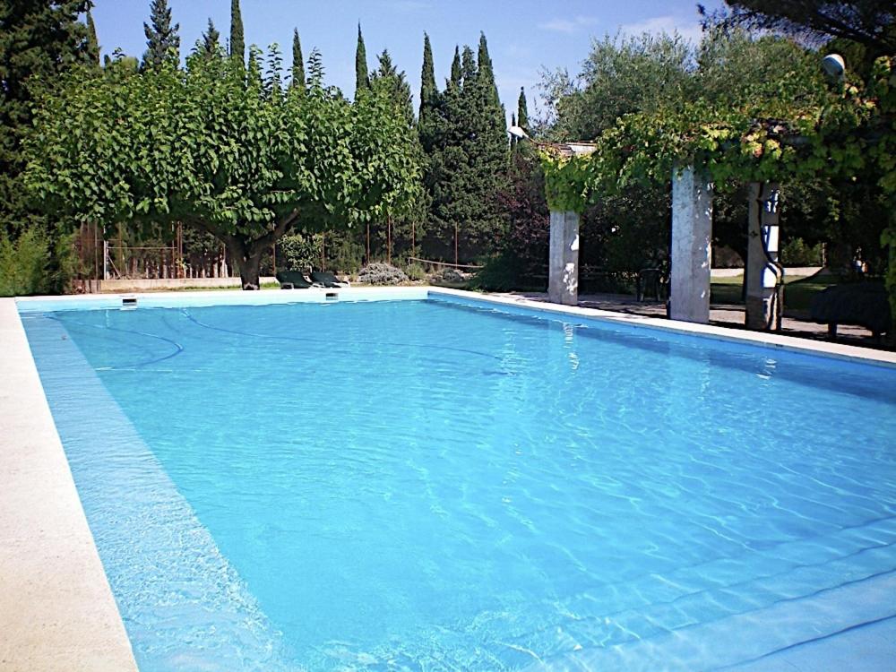 a large blue swimming pool with trees in the background at Casa Rural Aire in Muro de Alcoy