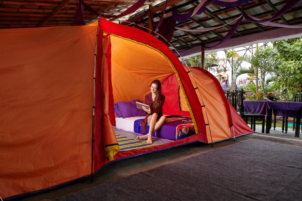 uma mulher sentada numa cama numa tenda em Hiker's Camp at Toya Devasya em Kintamani