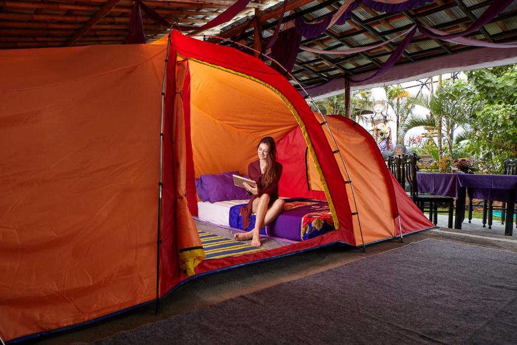 a woman sitting on a bed in a tent at Hiker's Camp at Toya Devasya in Kintamani