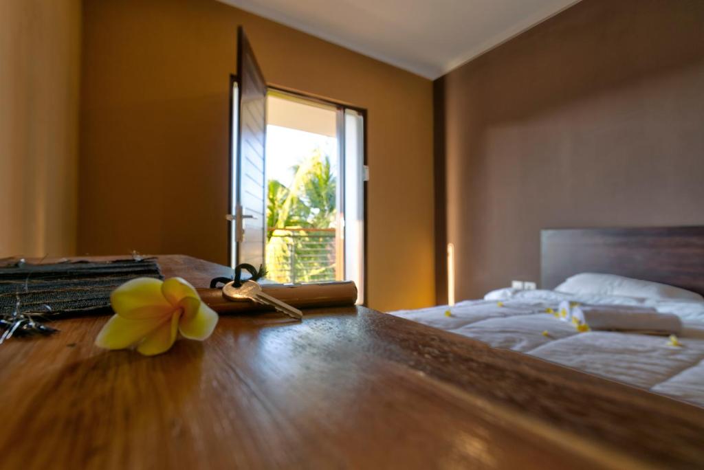 a bedroom with a bed and a table with a flower on it at Melody Guest House in Jimbaran
