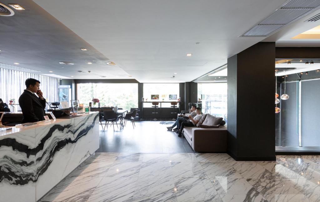 A spacious, polished lobby with a marble reception desk, lounge seating and bar-style counters.