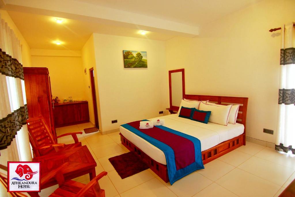 a bedroom with a bed and a chair in it at Athkandura Hotel in Habarana