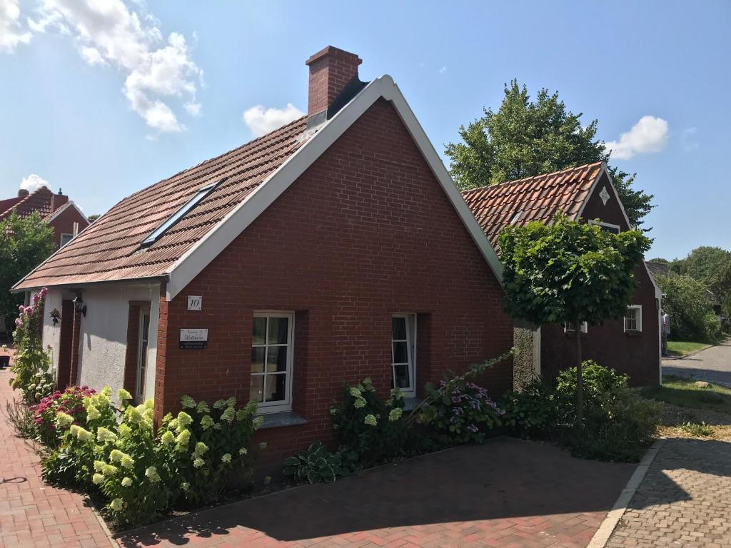 een oud rood bakstenen huis met een dak bij Ferienhaus Wattwurm in Rysum