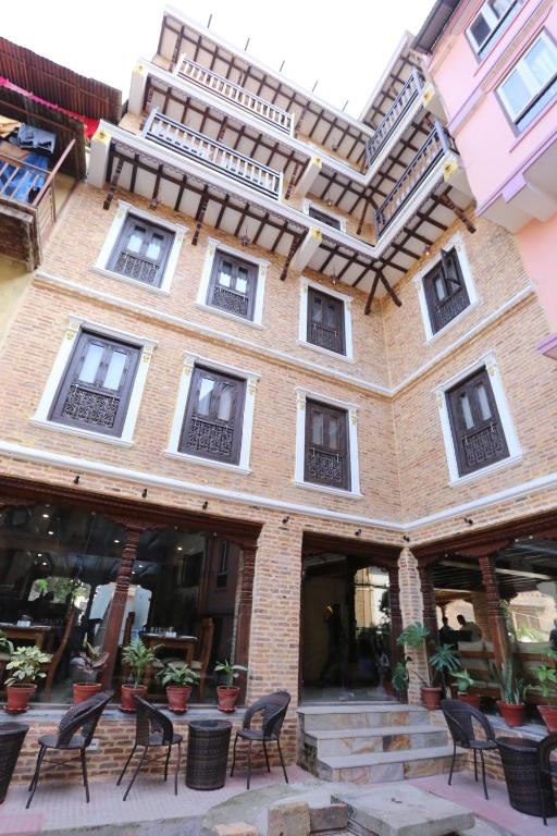 
a building with a patio area with tables, chairs and umbrellas at Pahan Chhen - Boutique Hotel in Kathmandu
