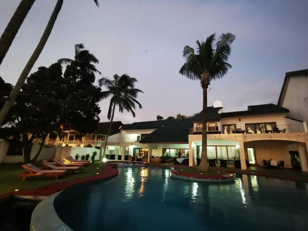 uma piscina com palmeiras em frente a um edifício em Résidence Hôtelière Océane em Libreville