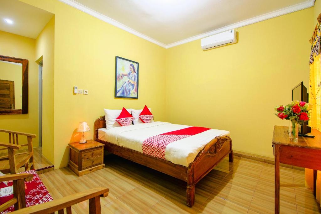 OYO 2047 Opak Village Bed & Breakfast في بانتول: غرفة نوم بسرير في غرفة بجدران صفراء