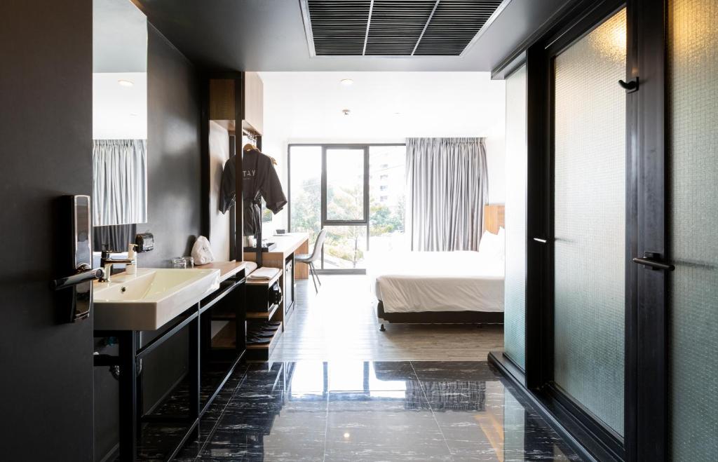 An open-plan room viewed from the bathroom entrance, with vanity, desk and bed.
