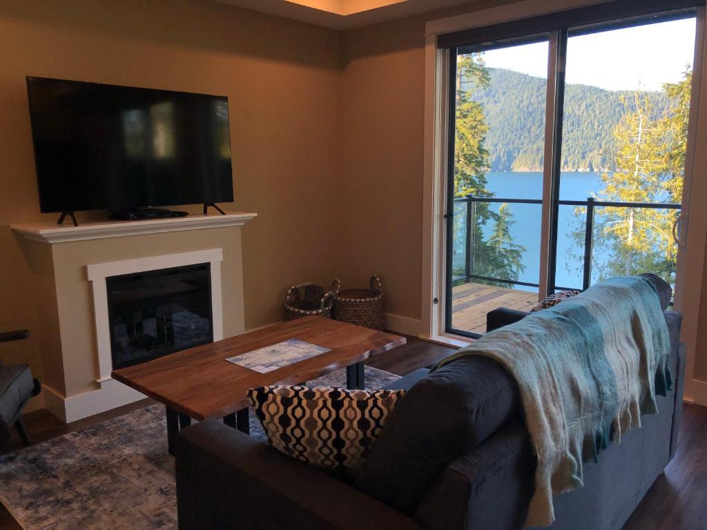 een woonkamer met een bank en een groot raam bij Botany Bay by Eagle Reach Properties in Port Renfrew