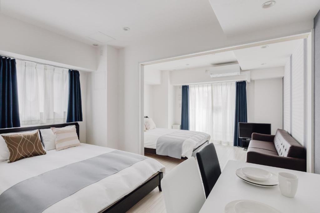 - une chambre avec 2 lits, une table et un canapé dans l'établissement BON Condo Namba Nipponbashi, à Osaka