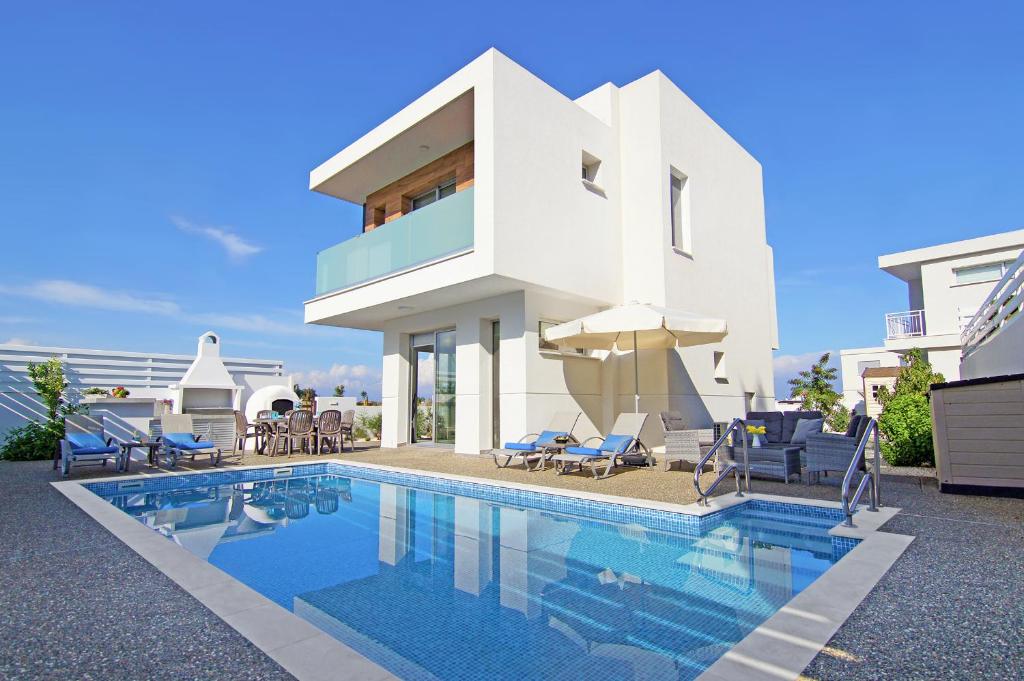 uma casa com piscina em frente a uma casa em Villa Thea Athena em Protaras