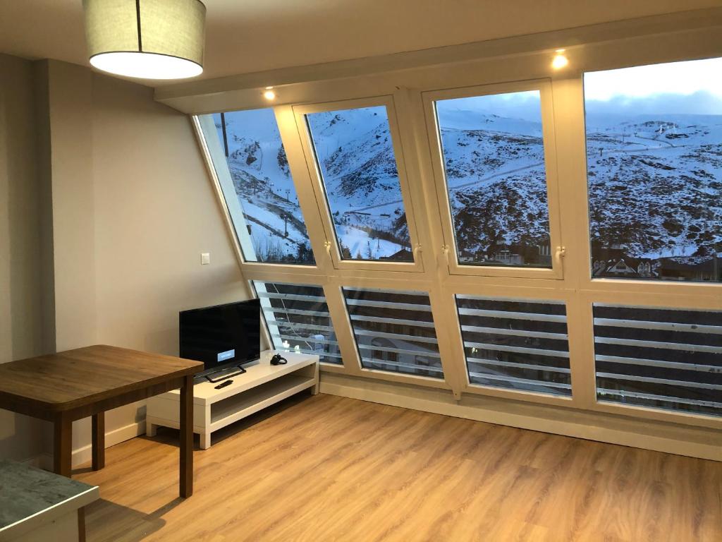 Habitación con ventana grande, escritorio y TV. en Apartamento Plaza Pradollano 1, en Sierra Nevada