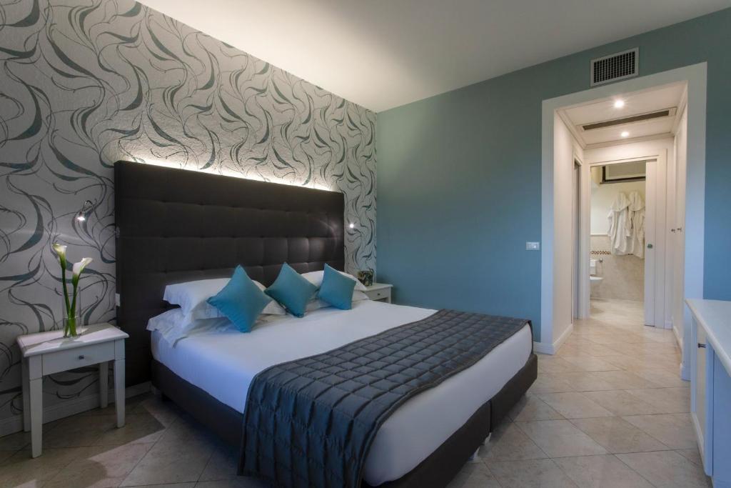 a bedroom with a large bed with blue pillows at Hotel Airone isola d'Elba in Portoferraio